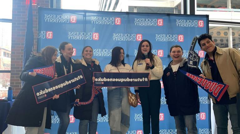 Admitted students celebrating at an admitted student event with signs that read FUTURE DUQUESNE DUKE