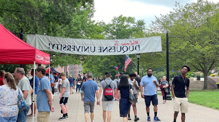 families exploring campus at an event under a WELCOME TO DUQUESNE UNIVERSITY BANNER